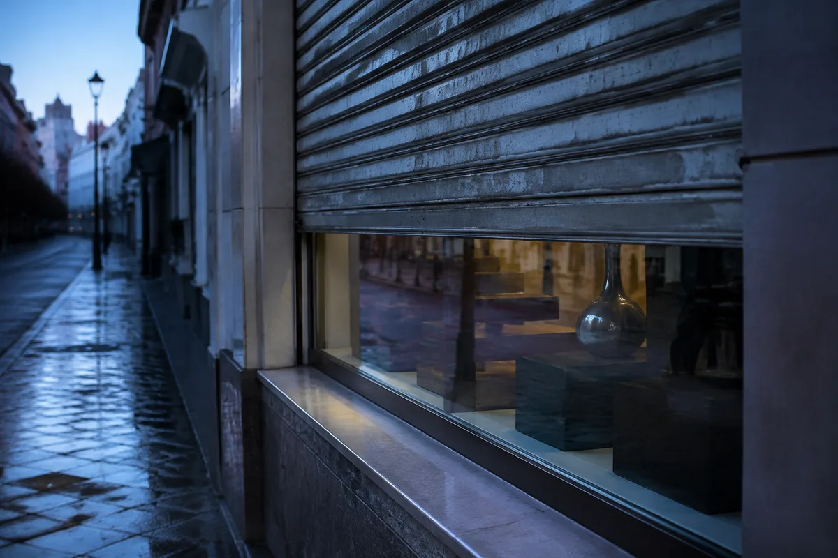 Vitrine et rideau métallique d’une boutique de quartier au petit matin, rue déserte