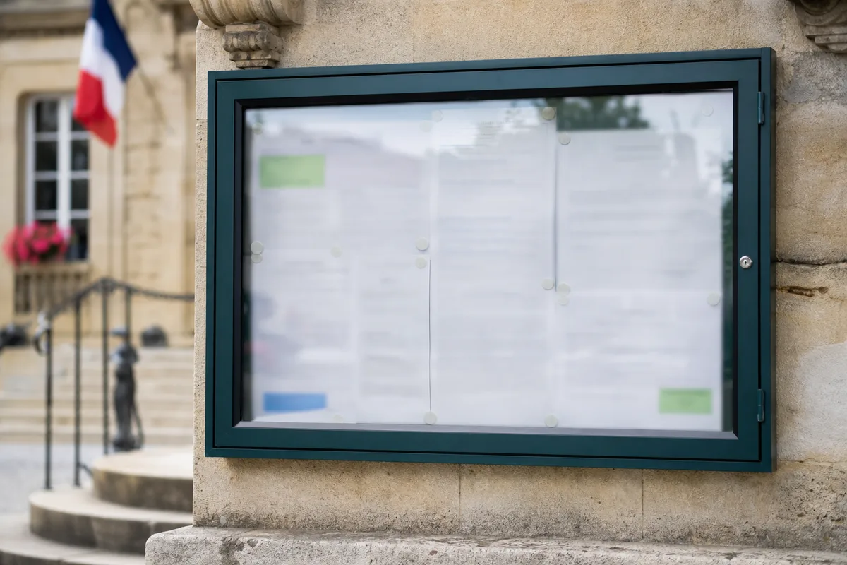 Panneau d&rsquo;affichage municipal devant une mairie de petite ville, arrêtés placardés sous vitrine